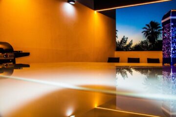 Una scena rilassante di uno spazio esterno con piscina illuminata da luci calde e moderne.