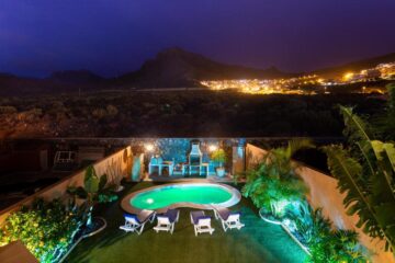 Una villa di lusso dal design architettonico classico e colorato, illuminata da luci notturne.