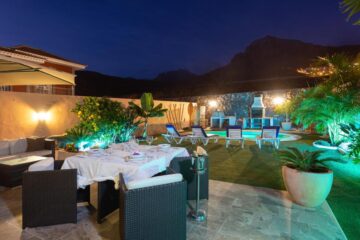 Una villa di lusso dal design architettonico classico e colorato, illuminata da luci notturne.