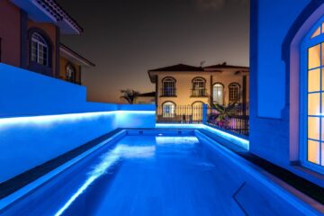 Una piscina illuminata di notte da luci blu crea un'atmosfera rilassante e sofisticata.
