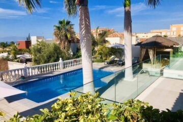 Una splendida villa moderna con piscina di design circondata da palme e vegetazione lussureggiante.