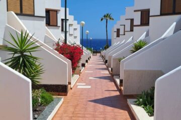Un vicolo in stile mediterraneo con case bianche e finestre scure, tipico di un ambiente costiero.